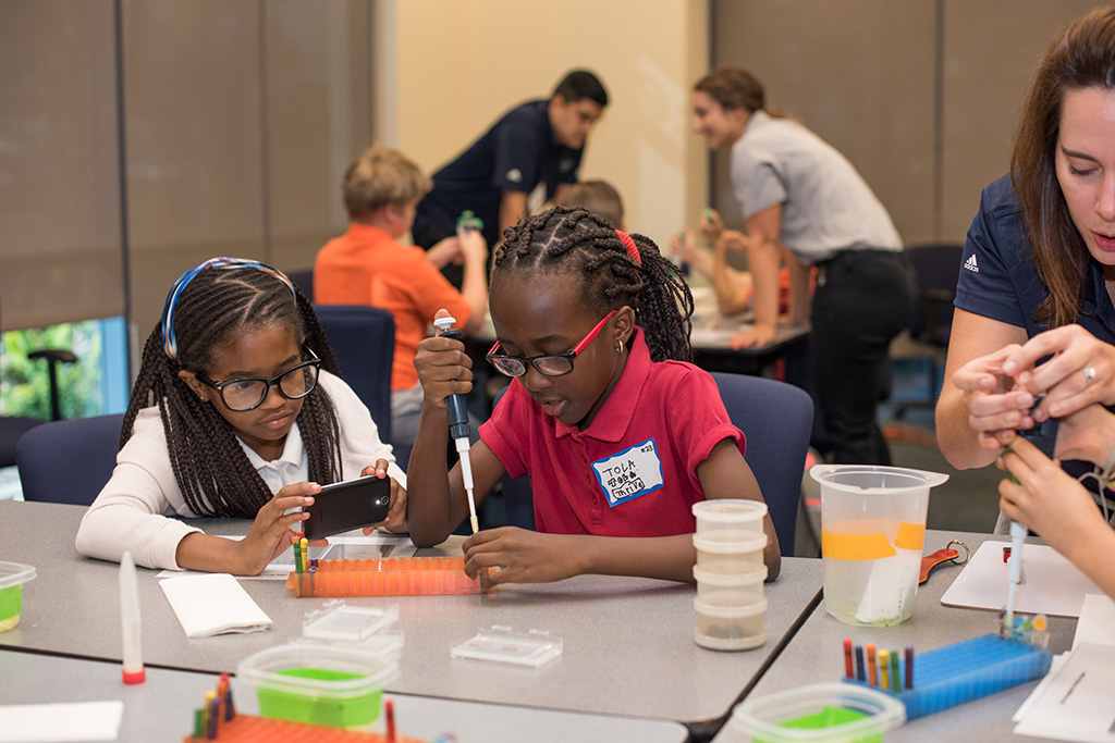 two girls use pipettes in a classroom