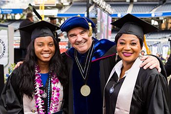 President Andrews poses with two graduates