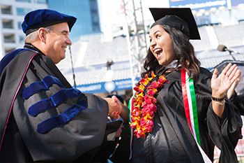 woman shakes a mans hand as she graduates