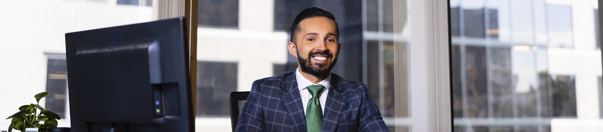 man in a plaid suit sits at a desk in an office