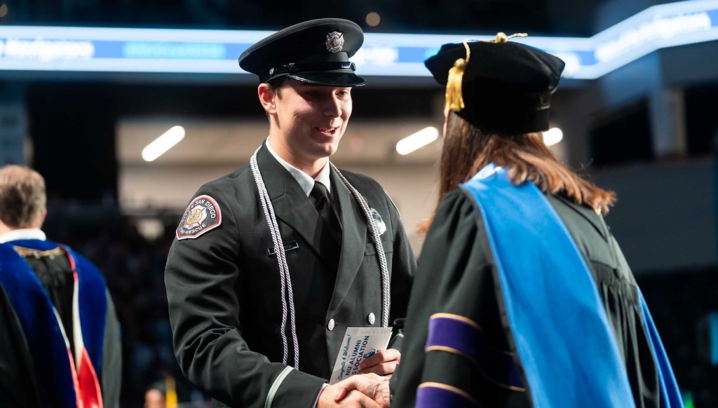 Public service member shaking hand on stage at commencement