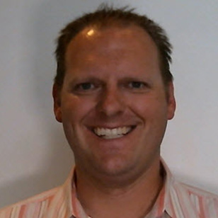 Headshot of Dirk Epperson in an orange dress shirt
