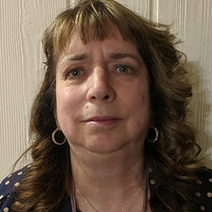 Headshot of Dr. Nancy Golden, who has bangs and wavy hair. She wears a dark blouse and hoop earrings