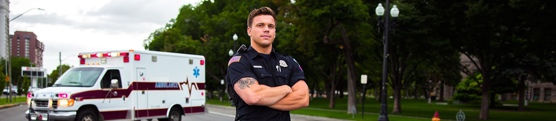 Jackson M. stands in uniform with his arms crossed in front of an ambulance