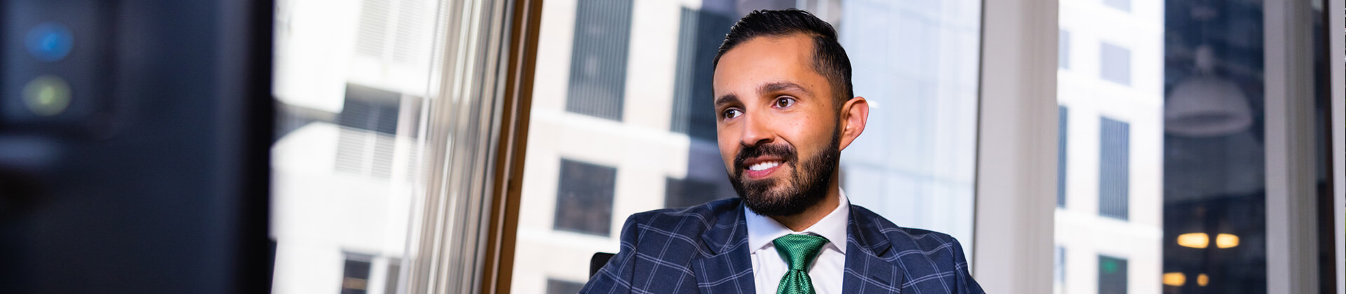 Man with a beard in a plaid suit sits in an office