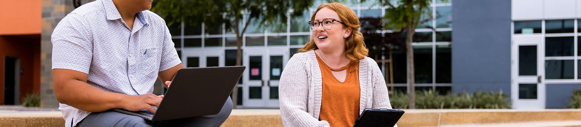 Brittney H. - Class of 2021, talks to a colleague as they work on laptops outside NU