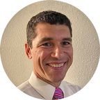 Headshot of Dr. Brian Tilley, PhD, MA in Counseling Associate Professor & Program Director, a clean-shaven man in a white shirt and printed tie