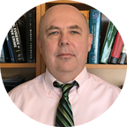 Headshot of Christopher Simpson, Academic Program Director, Master of Science in Cybersecurity, a bald man who wears a button down shirt and striped tie.