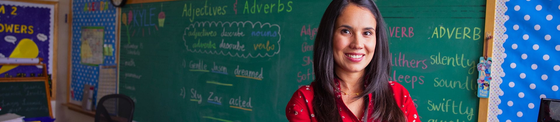 Abigail J. stands in front of a chalkboard in a classroom