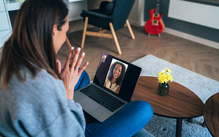Woman using laptop for video conference to connect with another person from home