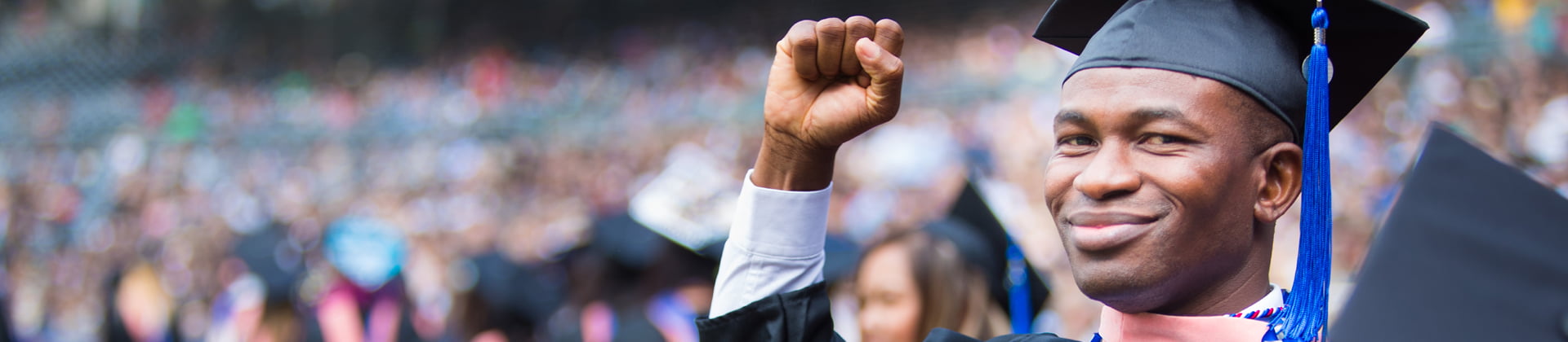 A graduate from NU holds his fist in the air at the graduation ceremony