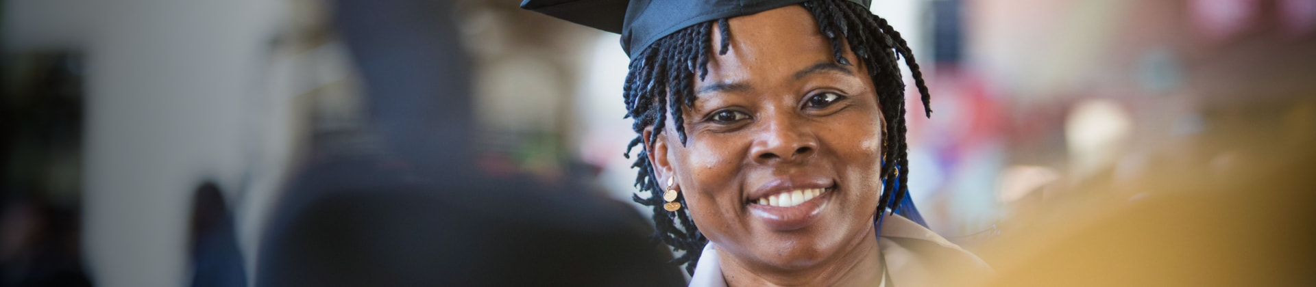Woman with short twists wears a cap and gown on her graduation day