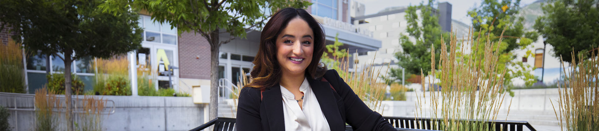 Balkis N., Class of 2019 woman sitting on bench outside smiling at camera