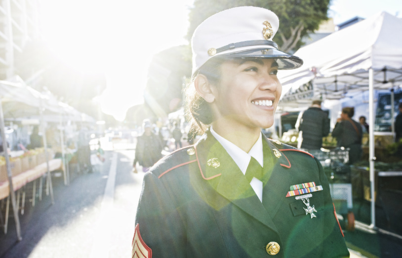 a woman servicemember in uniform stands outside in a farmer's market