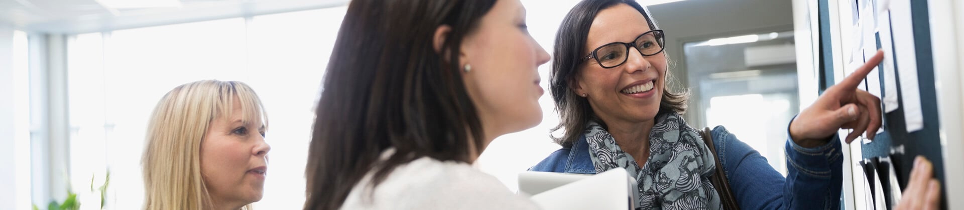 two women collaborate as a third woman looks on