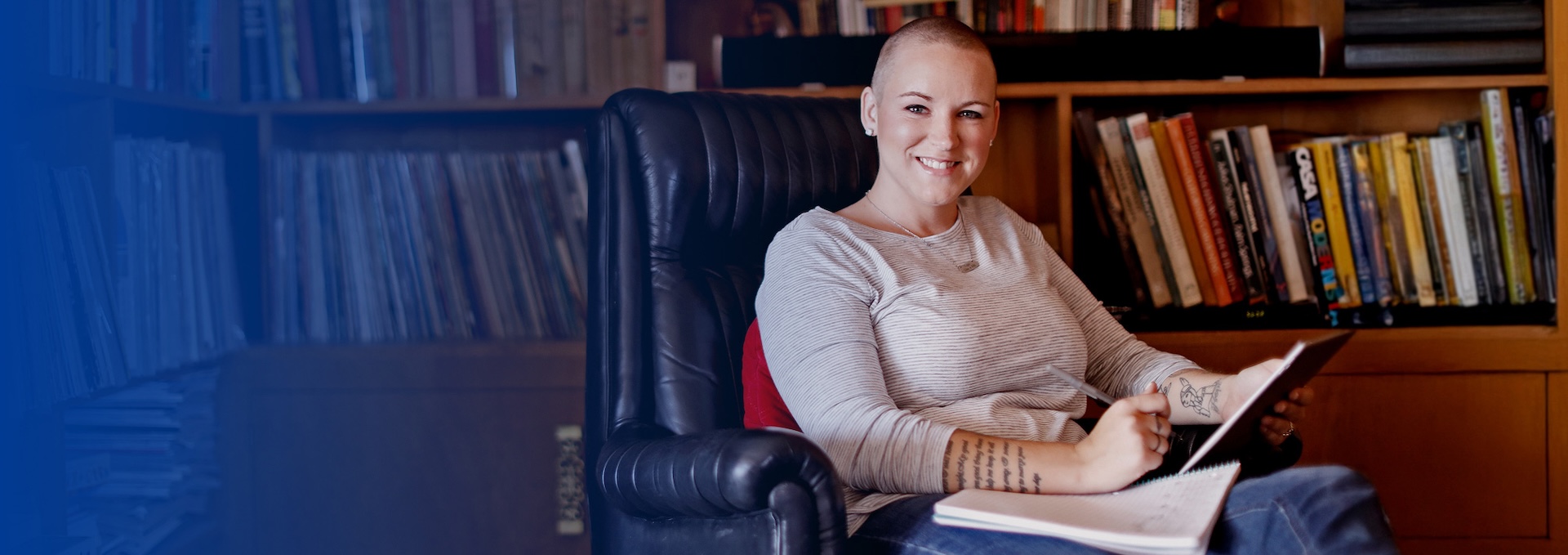 person sitting in leather chair in library with paper and pen