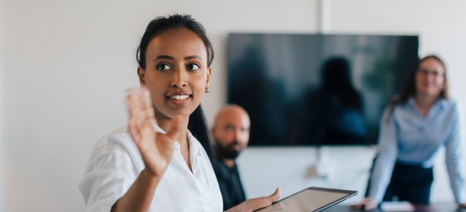woman raising her hand to ask a question while two colleagues look on behind her