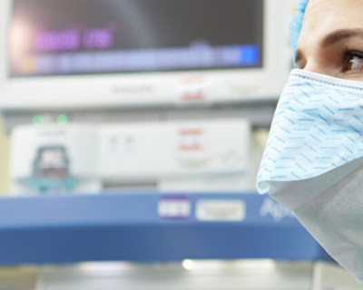 Nurse anesthesiologist in surgical room with scrubs and face mask looking on