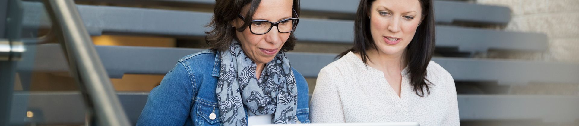 Two women look at a laptop for the Master of Arts in Education Program Page