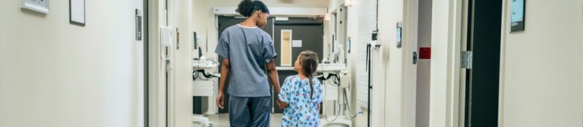 Nurse holding hand of little girl in hospital gown