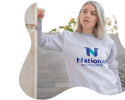 A woman in a National University sweatshirt leans on a stone wall