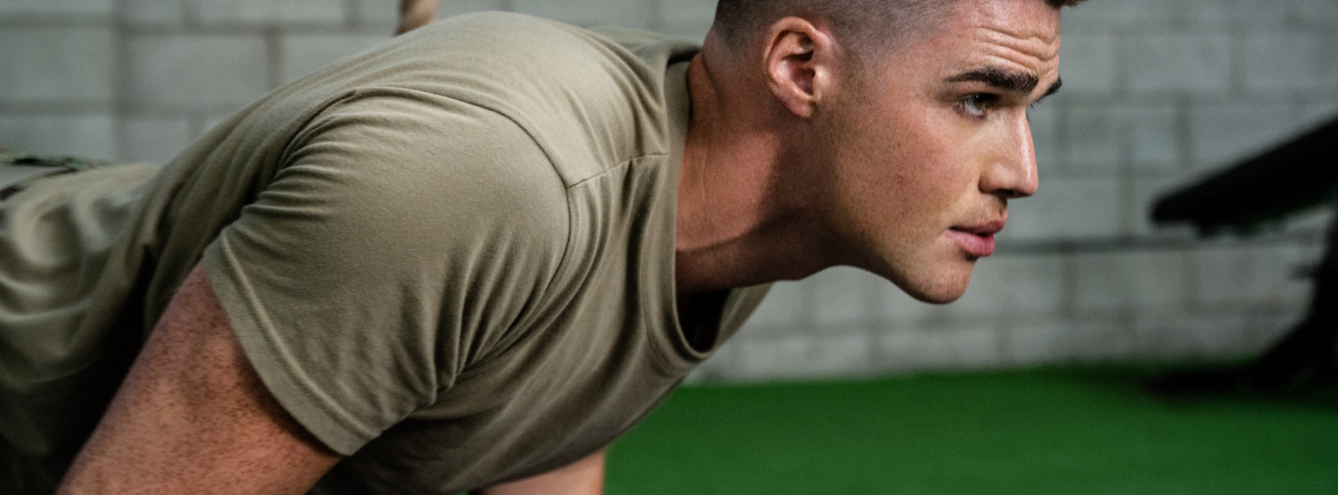 closeup of a man in military uniform doing pushups while he looks ahead