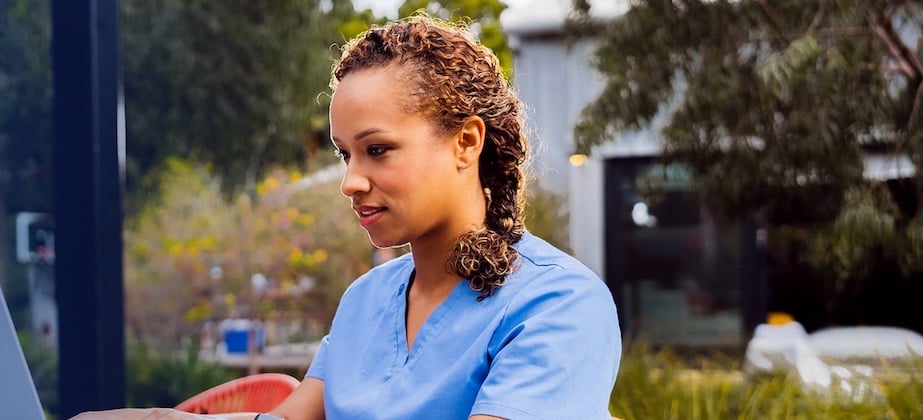 nurse sitting outside working on laptop