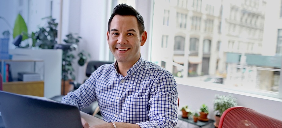 person sitting at desk with laptop and big window behind them