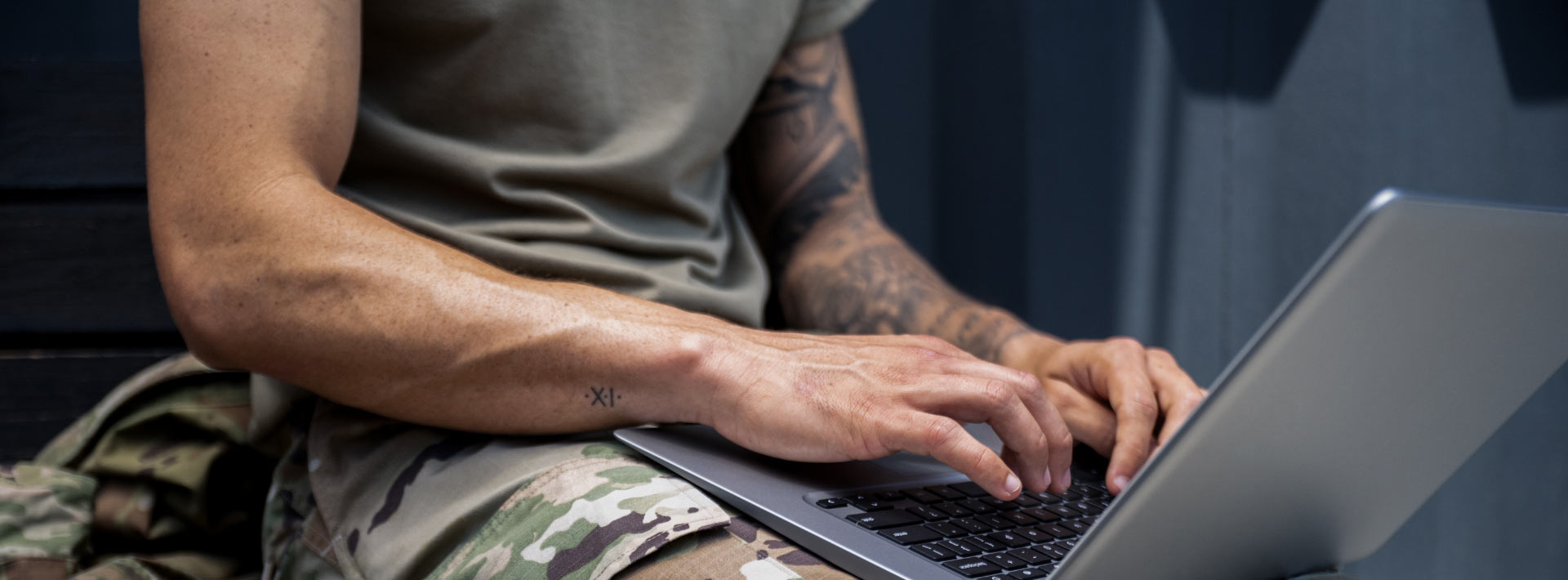 A man in a military uniform works with a laptop in his lap