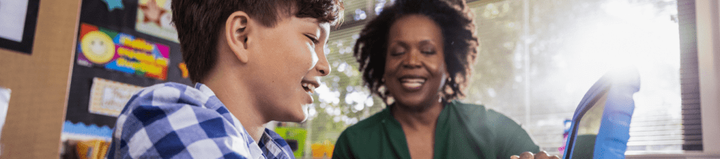 woman smiling at boy who is smiling at tablet