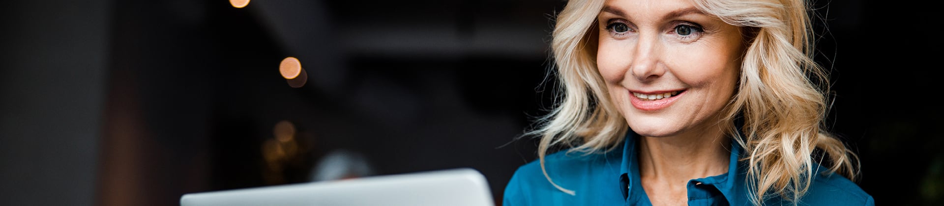 woman smiling as she gazes at a laptop 