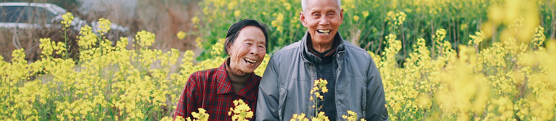 elderly couple smiling together in field