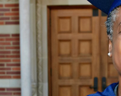 Person smiling wearing graduation cap and gown