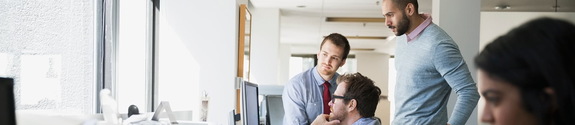 2 people looking over a man's shoulder as he works on a computer