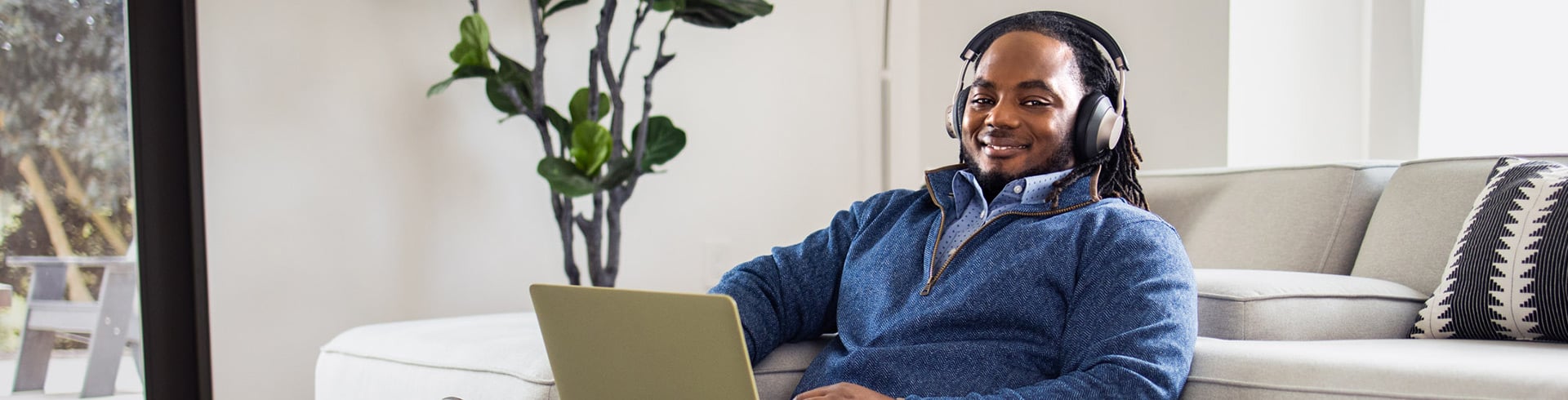 Man sitting on sofa with computer and headset 