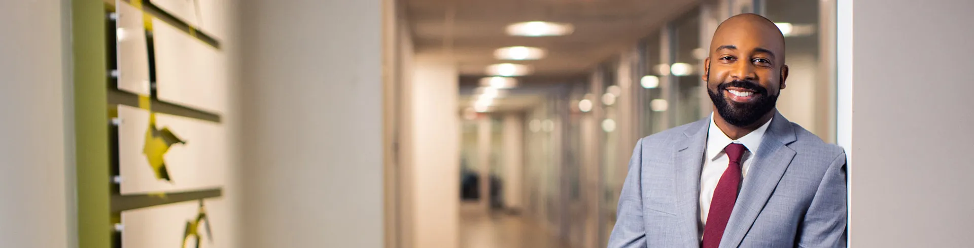 man in a gray suit stands in front of a hallway