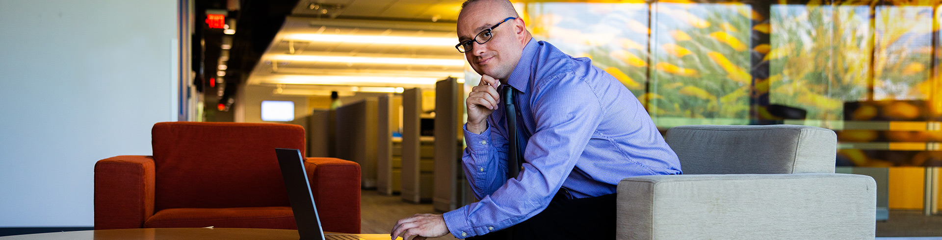 man sits in a lobby working on a laptop