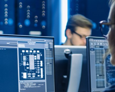 People working on computer in dark room with server racks