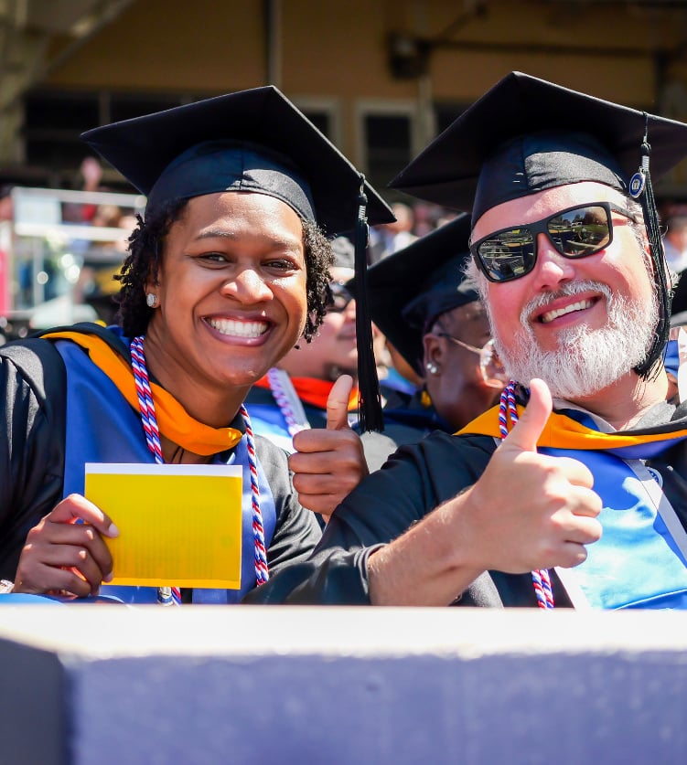 2 people giving a thumbs up at graduation