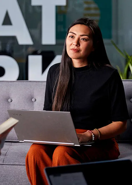 woman sits on a couch with a laptop on her lap