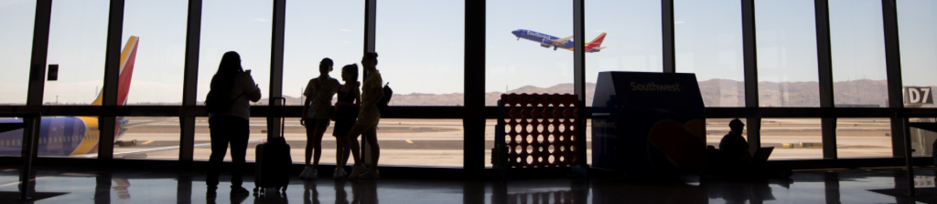 people taking a picture in airport terminal with Southwest Airlines plane taking off in the background