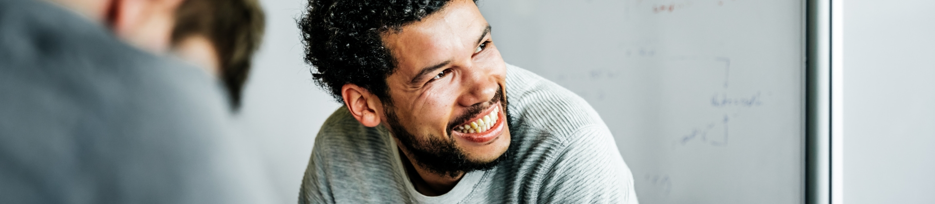 man in a gray sweater smiles