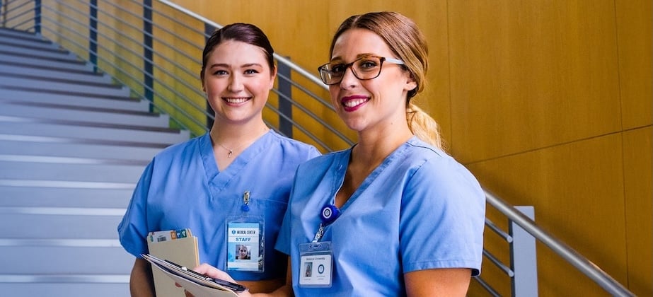 two nurses standing at bottom of stairs