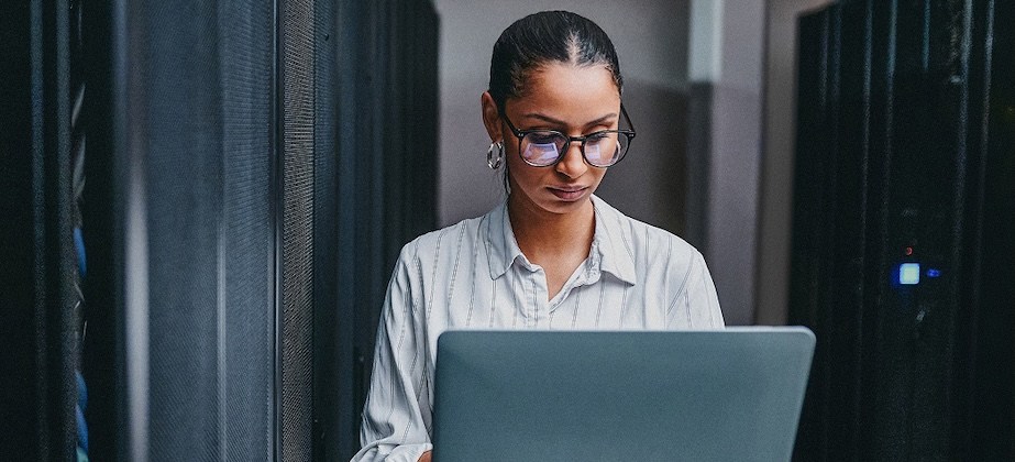 person working on laptops walking between servers