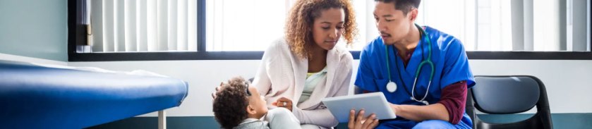 Man in nurse scrubs talking to a woman with a toddler