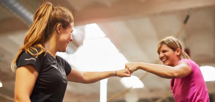 two women in gym fist pumping