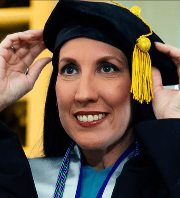 Person wearing cap and gown looking in the mirror
