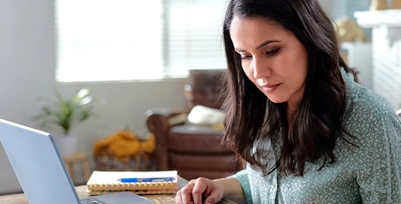 woman sitting at kitchen table working on laptop