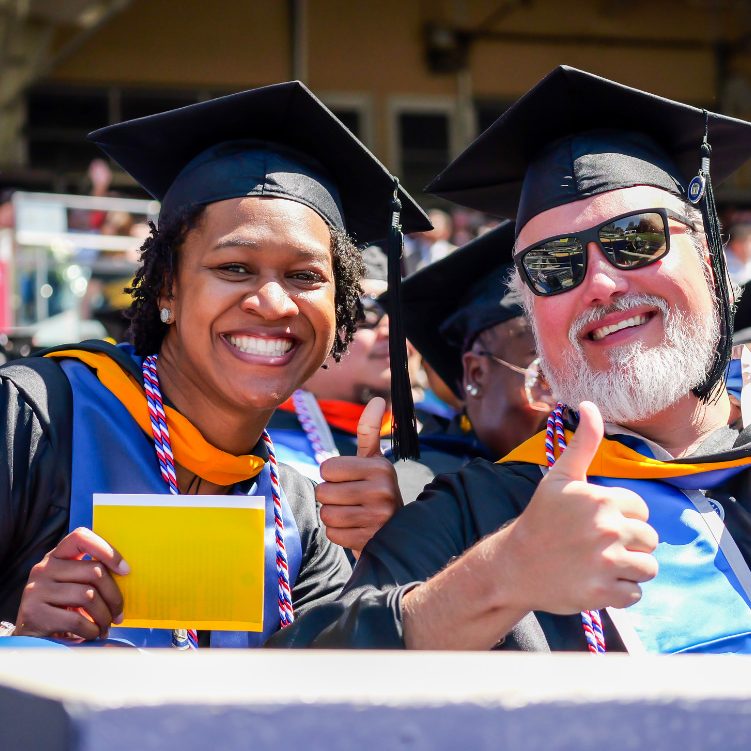 2 people giving a thumbs up at graduation