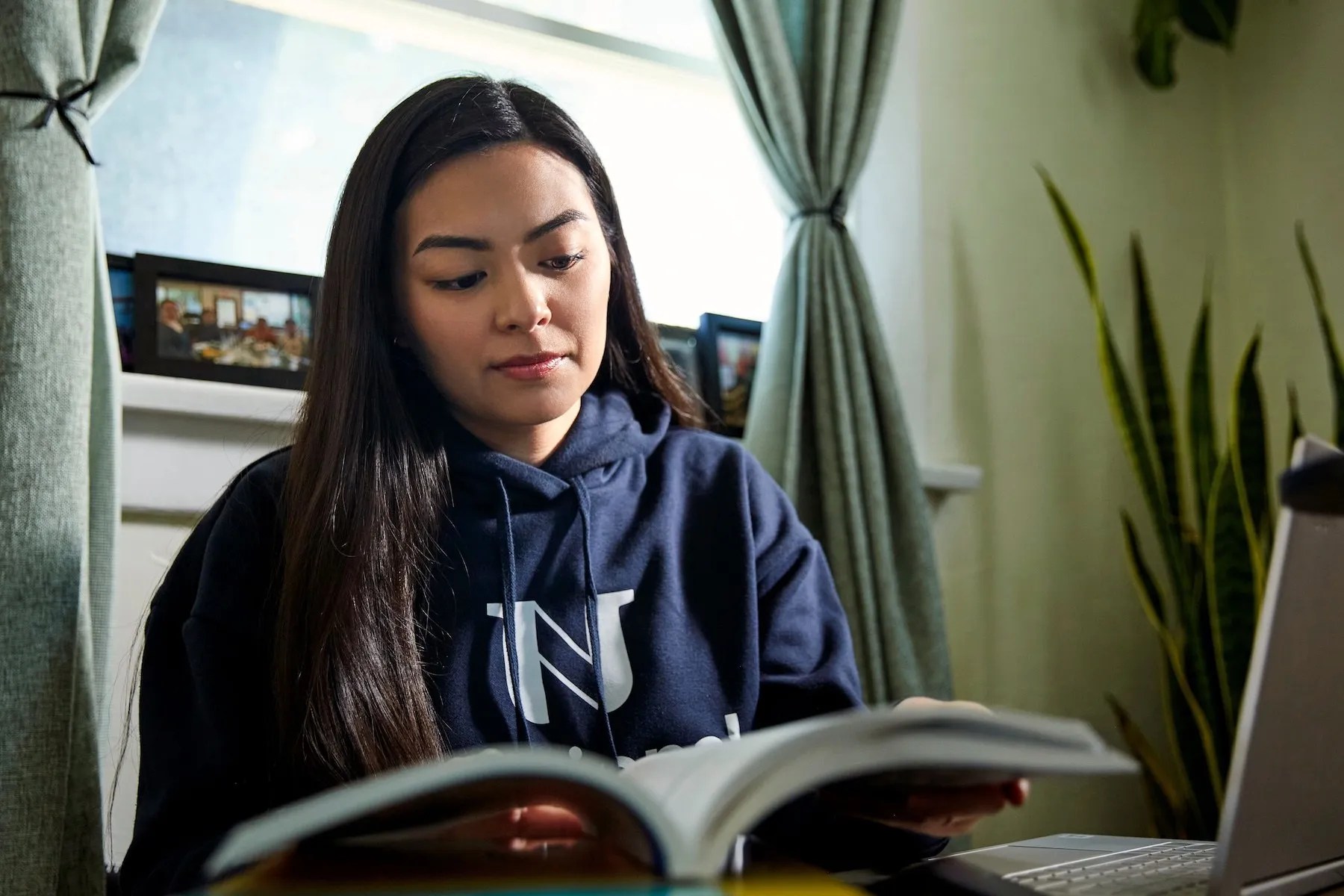 female student in NU shirt reading book